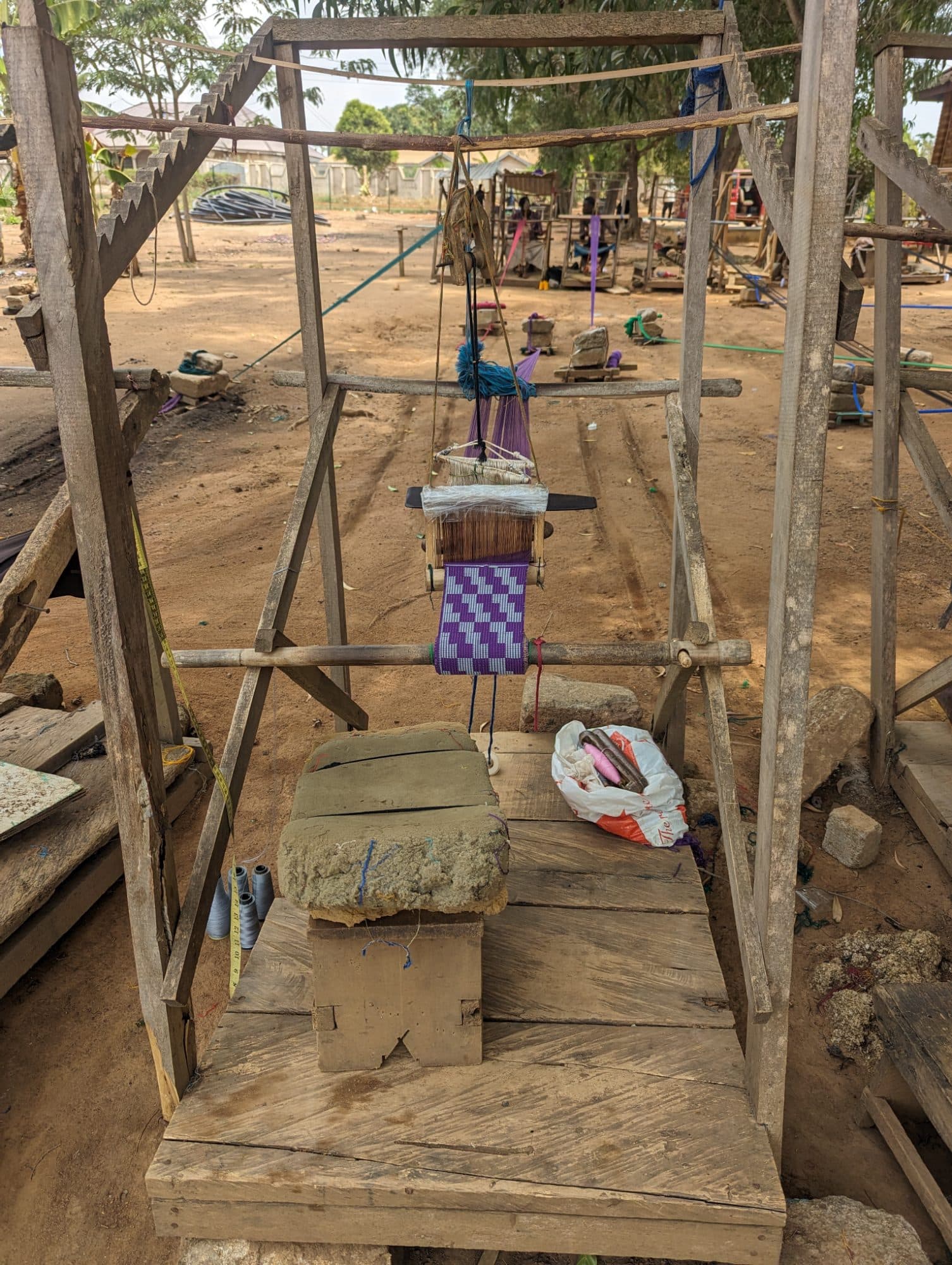 A wooden kente loom with a length of woven cloth